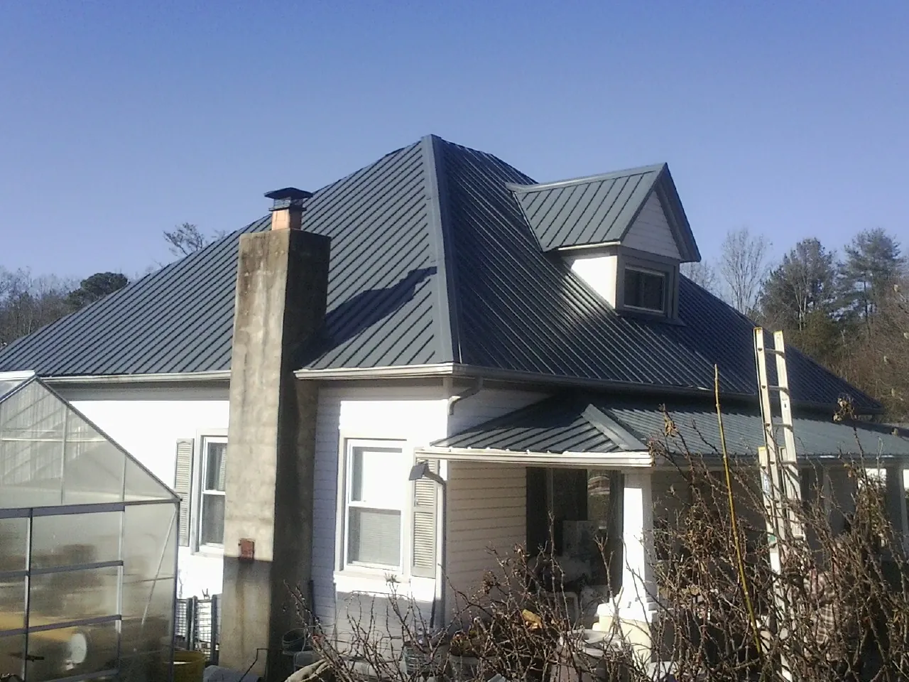 Dark blue standing seam metal roof on a white farmhouse with dormer — Slate & Tile Roof Repair by Roofing Brothers in Chuckey