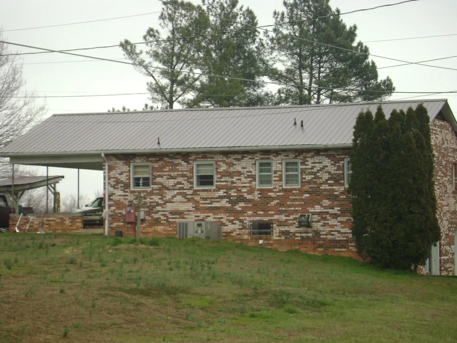 Gray metal roof on a brick split level home with a carport in Chuckey