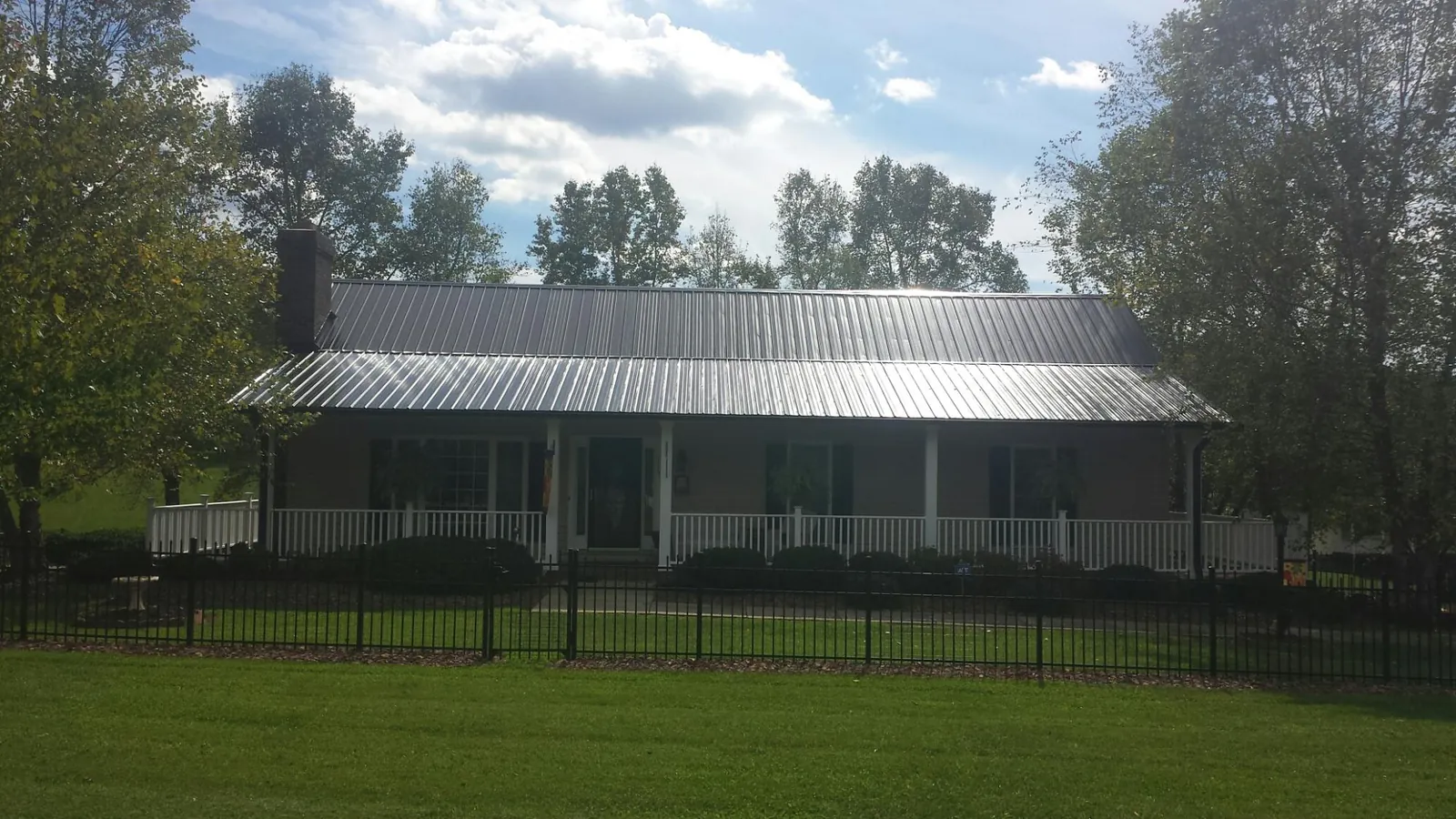 Gray metal roof on a brick ranch with a full width front porch — Gutter Guard Installation work by our crew in Chuckey