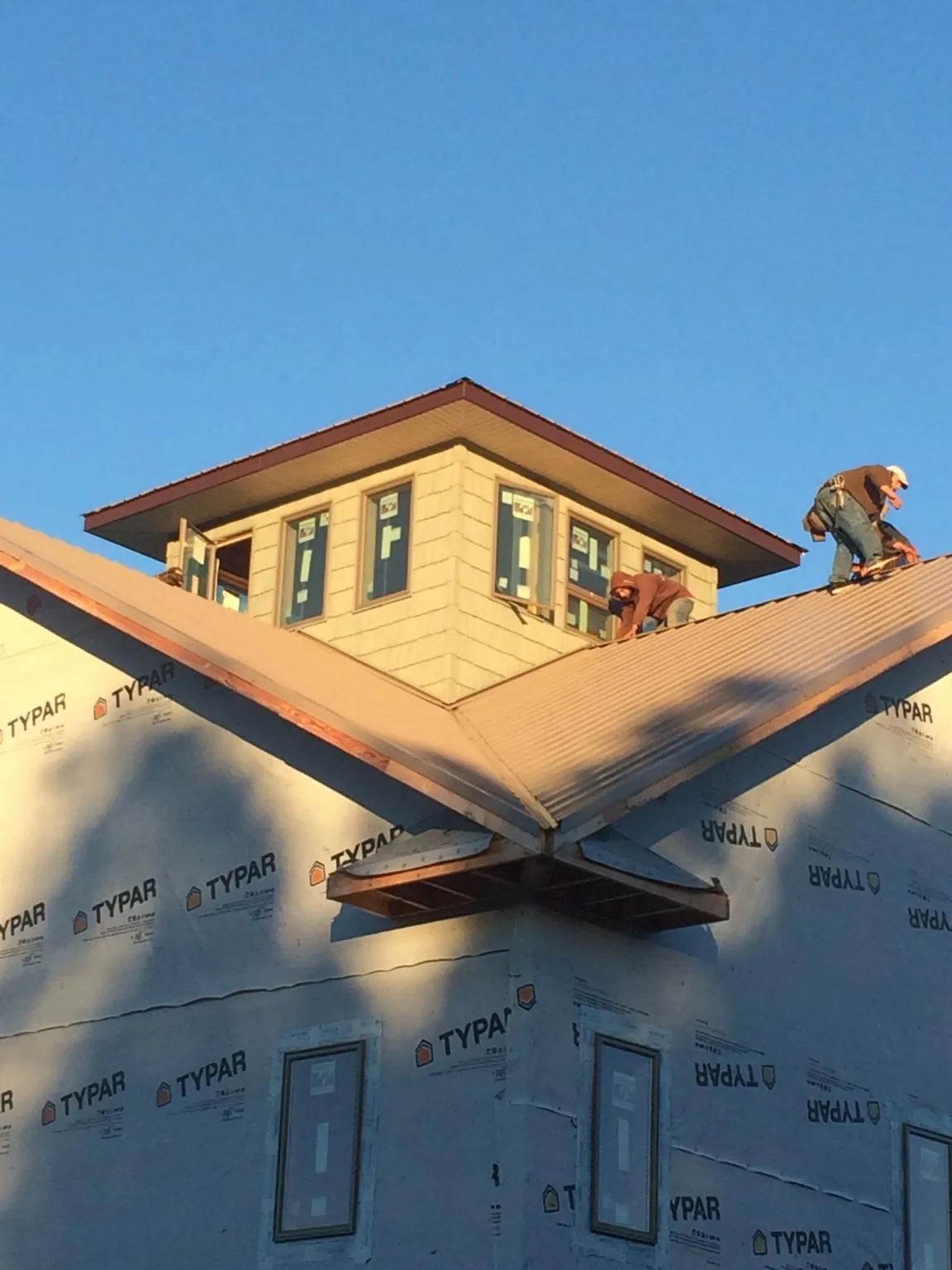 Roofers working around a rooftop cupola on a new metal roof at sunset — Roof Waterproofing in Chuckey by Roofing Brothers